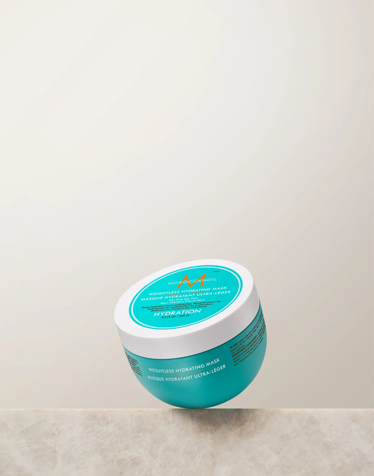 Turquoise Moroccanoil Weightless Hydrating Mask 250 ml jar with white lid on a light stone ledge
