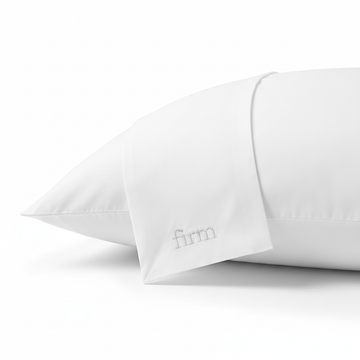 A firm pillow with a white cover, highlighting pillow protectors for hotels and Airbnbs for hygiene upgrade.