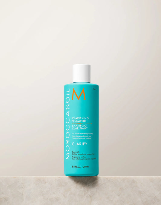 Turquoise Moroccanoil Clarifying Shampoo 250 ml bottle with white cap on a light stone ledge