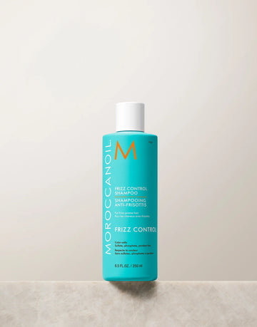 Turquoise Moroccanoil Frizz Control Shampoo 250 ml bottle with white cap on a light stone ledge