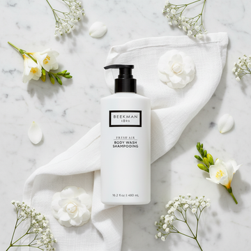 Beekman 1802 Fresh Air Body Wash luxury flat lay white frosted bottle with white flowers fresh linen on white marble - goat milk body wash clean fragrance