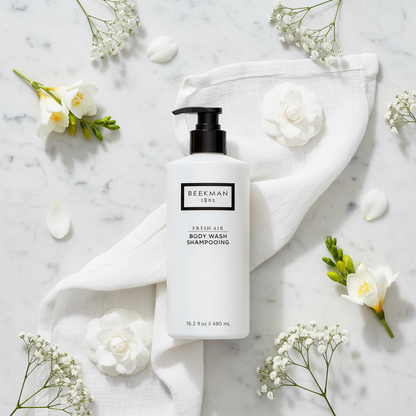 Beekman 1802 Fresh Air Body Wash luxury flat lay white frosted bottle with white flowers fresh linen on white marble - goat milk body wash clean fragrance