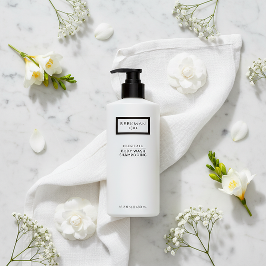 Beekman 1802 Fresh Air Body Wash luxury flat lay white frosted bottle with white flowers fresh linen on white marble - goat milk body wash clean fragrance