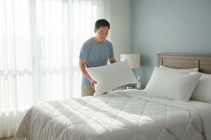 Asian man placing WoodSpring Ecoendure pillow at home guest room bringing hotel quality comfort home