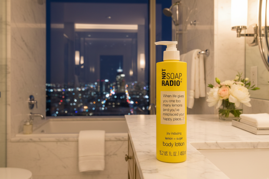Not Soap Radio lemon sugar body lotion 15.2 oz on white marble counter in luxury boutique hotel bedroom with stunning city skyline view at night - premium spa body lotion for hotels and Airbnb