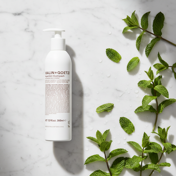 Malin+Goetz Peppermint Body Wash luxury flat lay with peppermint leaves on white marble - clean beauty body wash