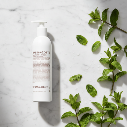 Malin+Goetz Peppermint Body Wash luxury flat lay with peppermint leaves on white marble - clean beauty body wash
