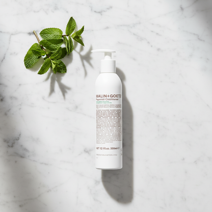Malin+Goetz Peppermint Conditioner luxury flat lay with peppermint on white marble - clean beauty hair conditioner