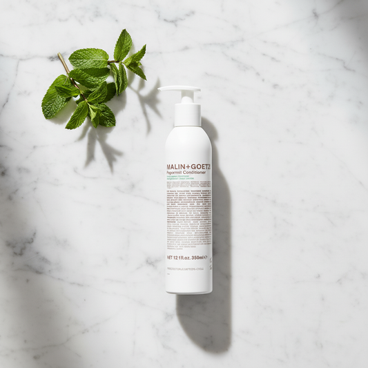 Malin+Goetz Peppermint Conditioner luxury flat lay with peppermint on white marble - clean beauty hair conditioner