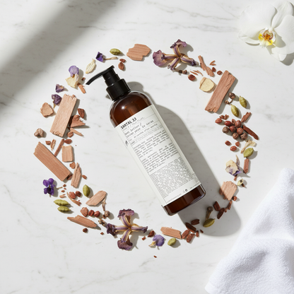 Le Labo Santal 33 Body Lotion - circular flat lay with sandalwood, iris, violet, cardamom on marble