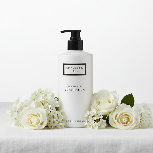 Beekman 1802 Fresh Air Body Lotion styled on white linen with fresh white flowers - luxury goat milk moisturizer clean fragrance