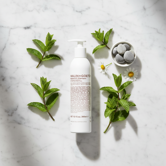 Malin+Goetz Peppermint Shampoo luxury flat lay with fresh peppermint leaves on white marble - clean beauty hair care