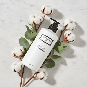 Beekman 1802 Fresh Air Conditioner luxury flat lay white frosted bottle with white cotton flowers eucalyptus on white marble - goat milk conditioner clean fragrance