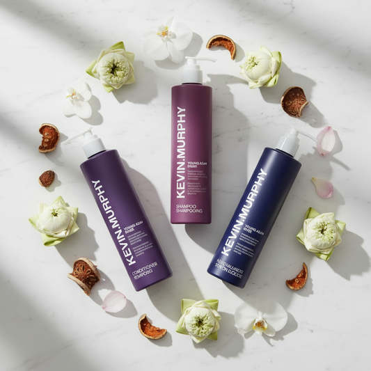Kevin Murphy Young.Again 3-Piece Set flat lay with orchid blooms and lotus flowers on white marble — luxury hotel hair and body care bundle