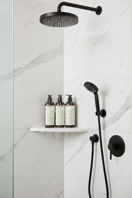 Le Labo Bergamote 22 Shampoo displayed in a modern shower with black fixtures and marble walls.
