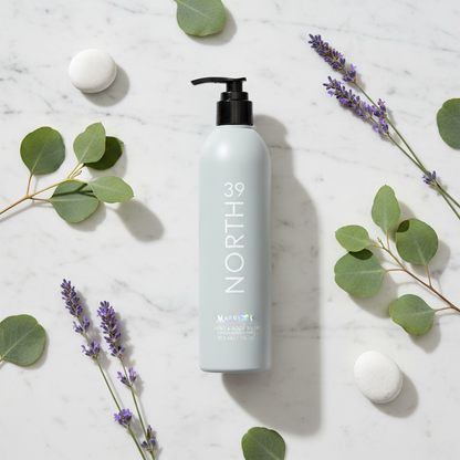 Marriott 39 North Hand & Body Wash 12 oz bottle surrounded by green leaves and purple flowers on marble surface.